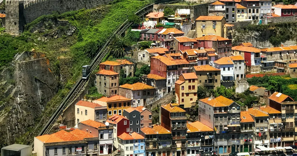 Orange-roofed houses and a funicular below a stone city wall in Porto