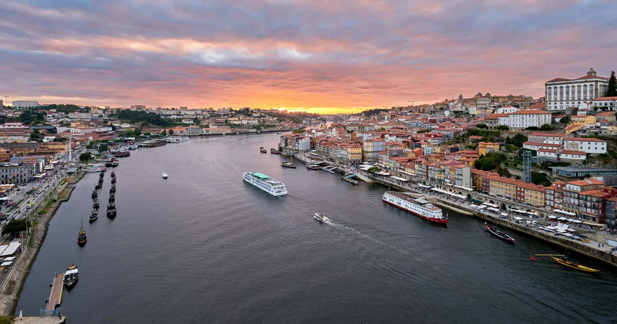 Aerial view of Porto riverside at sunset, with boats on the Douro and terracotta roofs along Ribeira