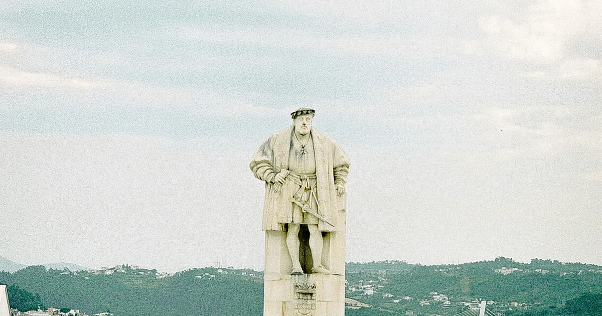 Stone statue of a man in sixteenth-century dress on a paved terrace, with hills beyond