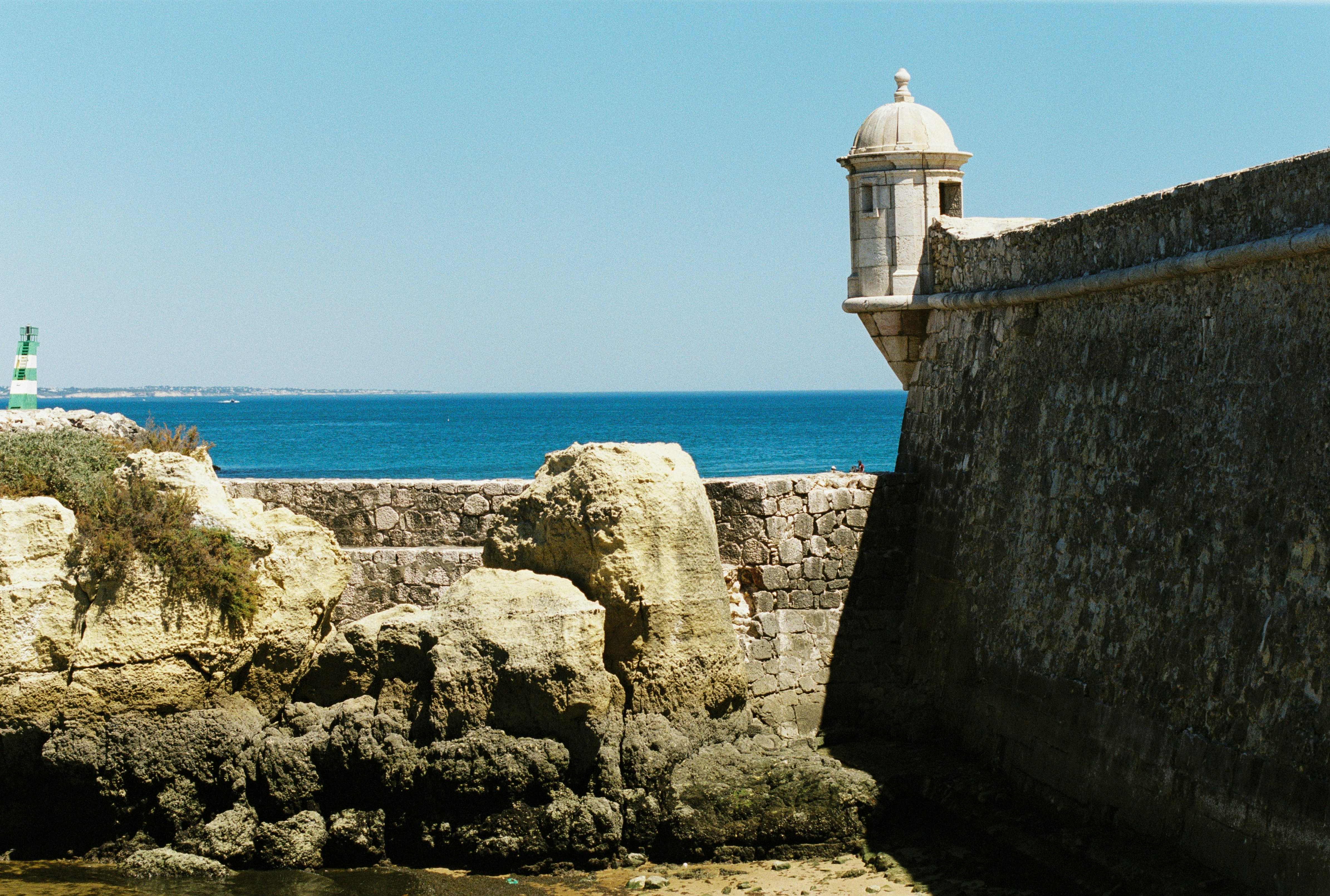 Stone seaward wall and sentry turret above limestone rocks, with open Atlantic water beyond