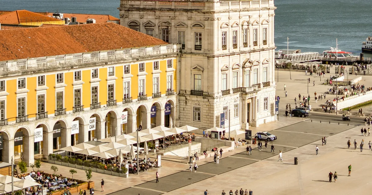 Yellow arcades and a white riverside palace on Praça do Comércio in Lisbon