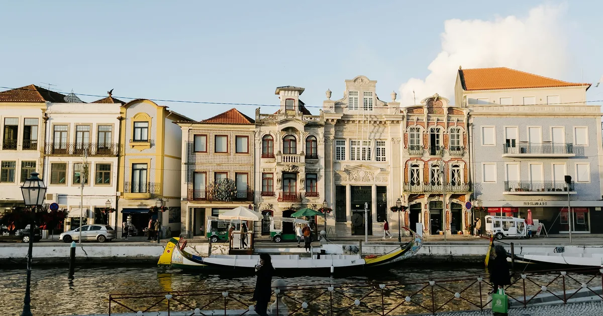 Canal-front row of ornate Portuguese townhouses, colorful boats, and pedestrians