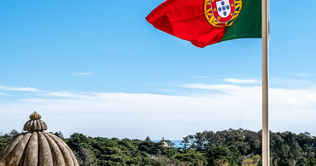 Portuguese flag on a white pole against a clear blue sky
