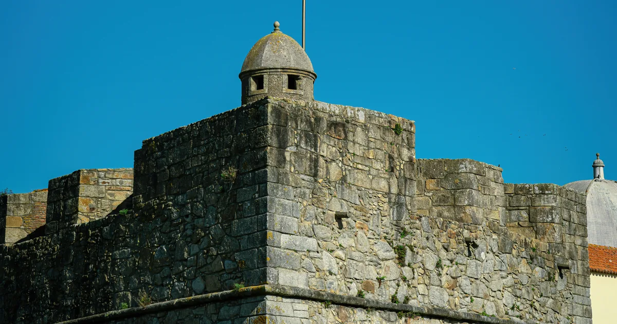 Stone fortress turret and masonry walls under a deep blue sky