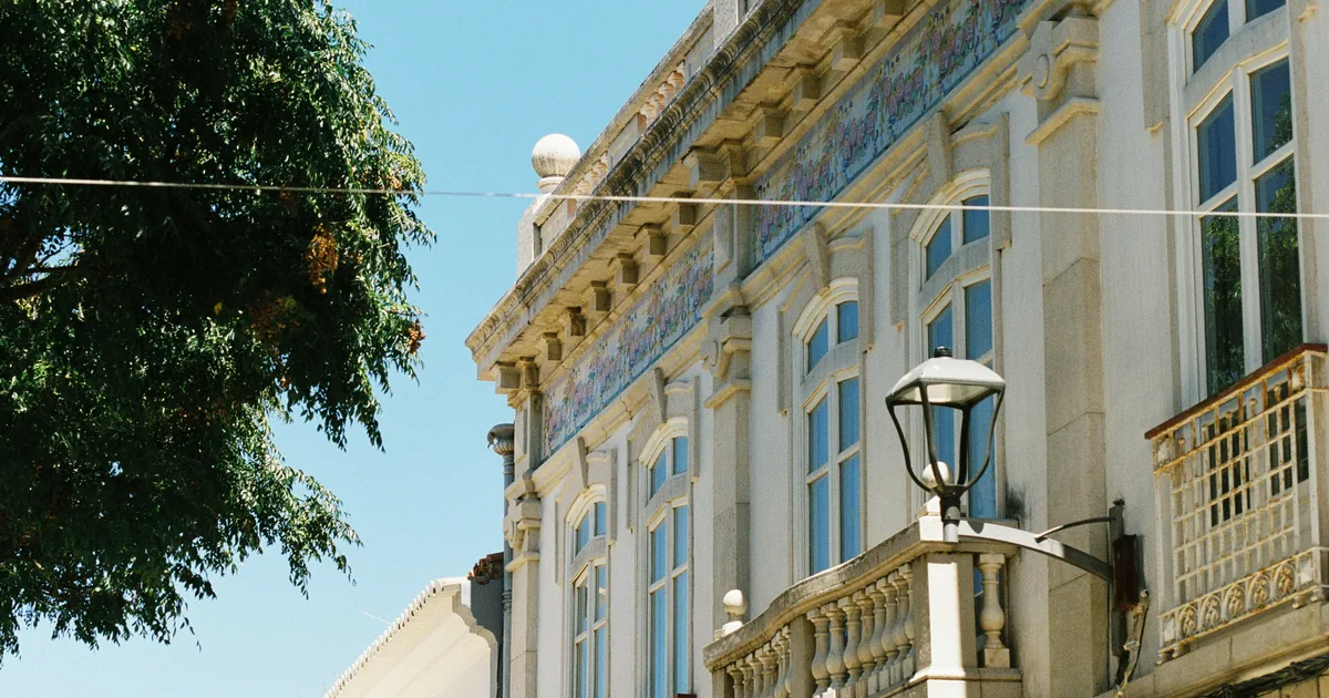 Cream facade with tiled lettering, stone balconies, and a black lantern