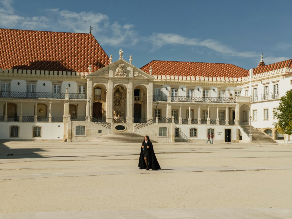 Student in traditional academic dress crossing the courtyard at the University of Coimbra, Portugal